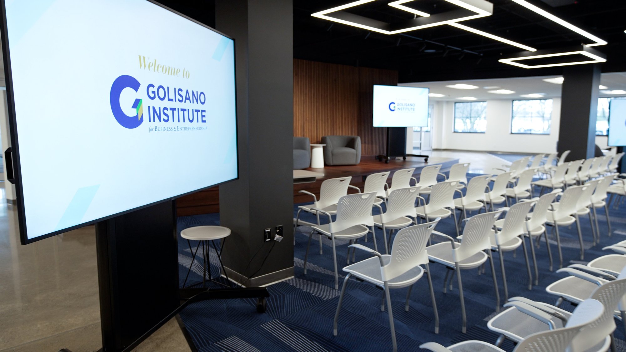 Modern AI Innovation Hub with curved wood-tone wall, central gathering space, and integrated technology for presentations and student lounge use.